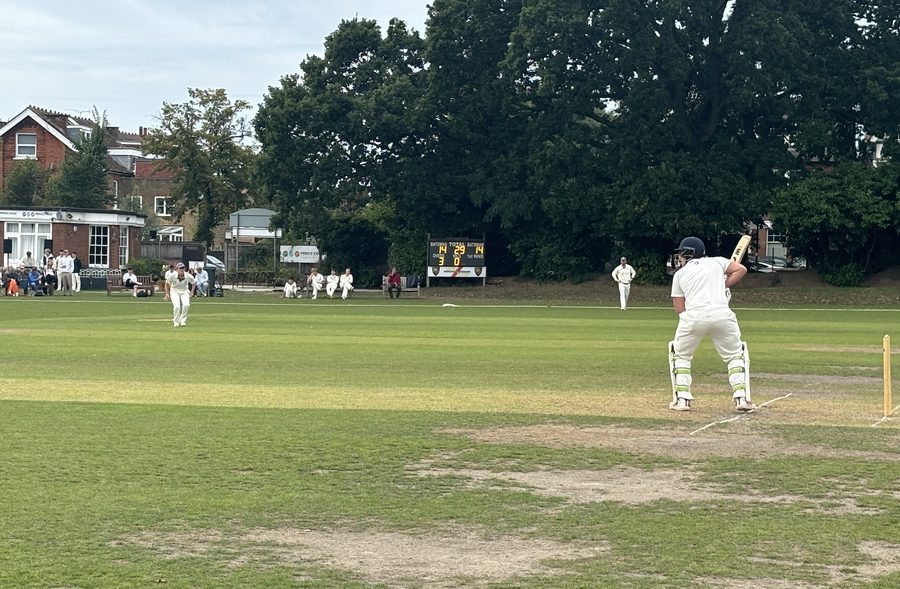 Batsman facing a delivery, scoreboard in the background